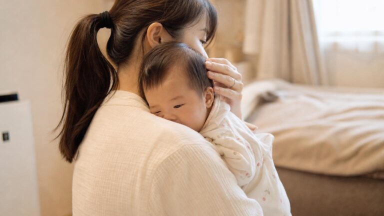 受診のあと、赤ちゃんをそっと抱いてあやす親の横顔。やわらかな室内の光